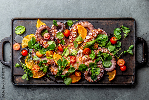 Whole octopus salad with orange, tomatoes and cress salad served on board with wine