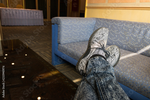 Relaxing of man who is crossing his feet while wearing the gray shoe with stripes pattern
