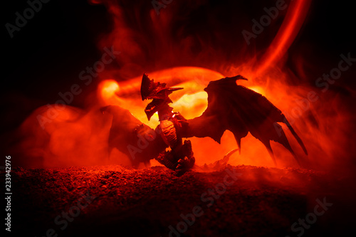 Silhouette of fire breathing dragon with big wings on a dark orange background © zef art