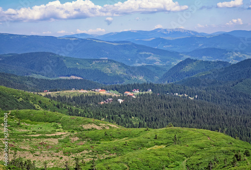 Green fir trees and houses of the village against the background of the Carpathian mountains in the summer. Dragobrat, Ukraine.Travel adventure and hiking activity lifestyle on family summer vacation
