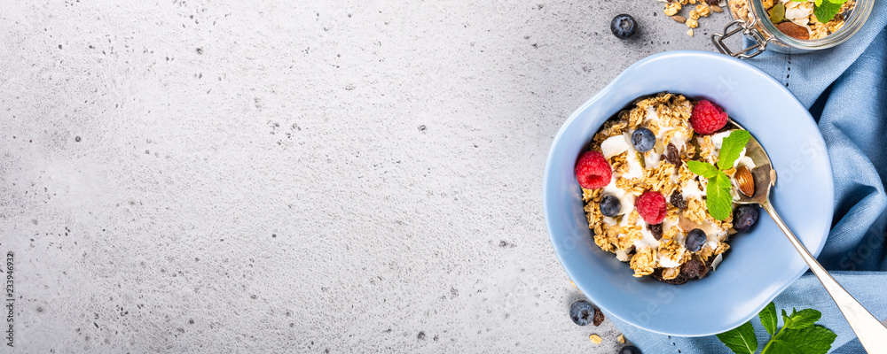Healthy food background with homemade oatmeal granola or muesli with yogurt and fresh berries for healthy morning breakfast, top view, copy space. Banner.