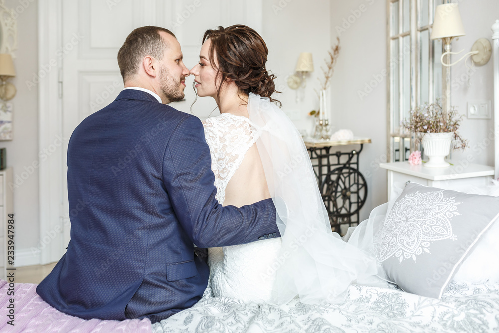 young beautiful girl bride sits on a bed with groom young beautiful girl bride sits on a bed with groom