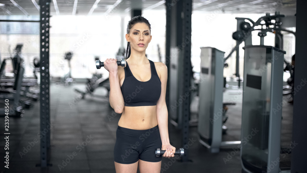 Fit woman lifting dumbbells in gym, arm muscles training, sportive lifestyle Fit woman lifting dumbbells in gym, arm muscles training, sportive lifestyle
