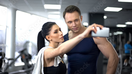 Young man and woman taking selfie in gym, modern technology, social networking