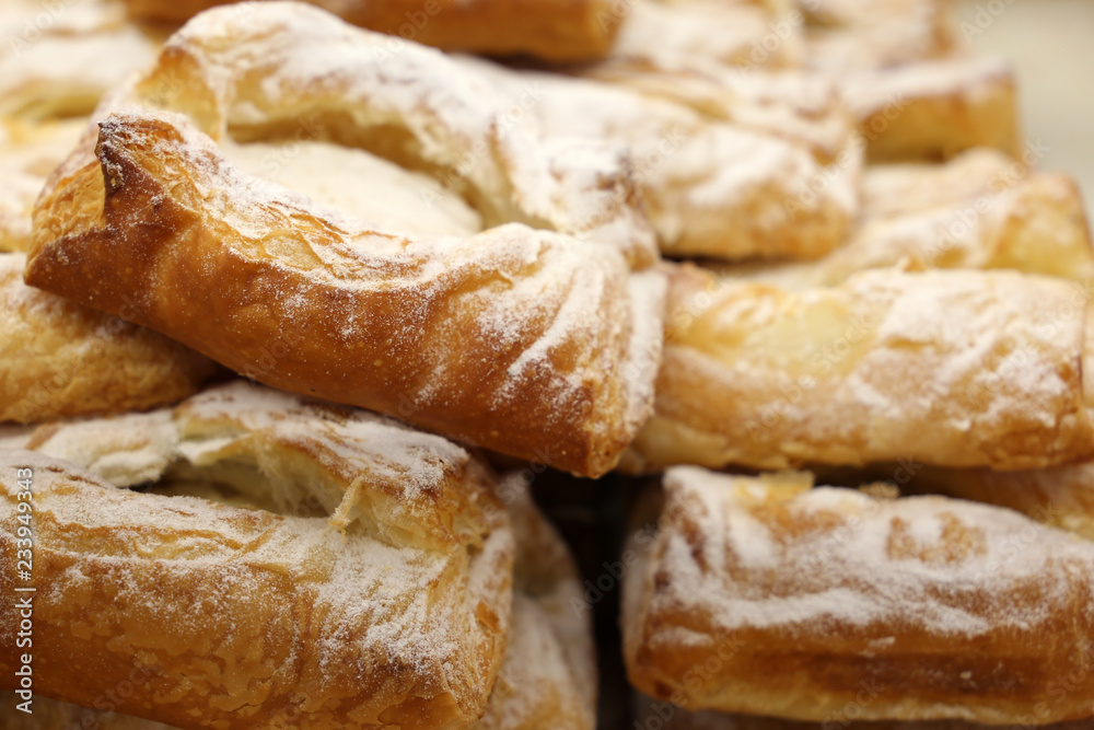 Puff pastry with powdered sugar and cottage cheese filling, close-up. Freshly baked rolls in the bakery, dessert for breakfast