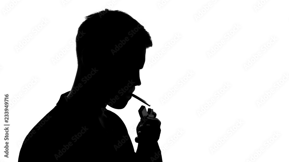 Young male silhouette lighting cigarette and smoking, unhealthy addiction cancer Young male silhouette lighting cigarette and smoking, unhealthy addiction cancer