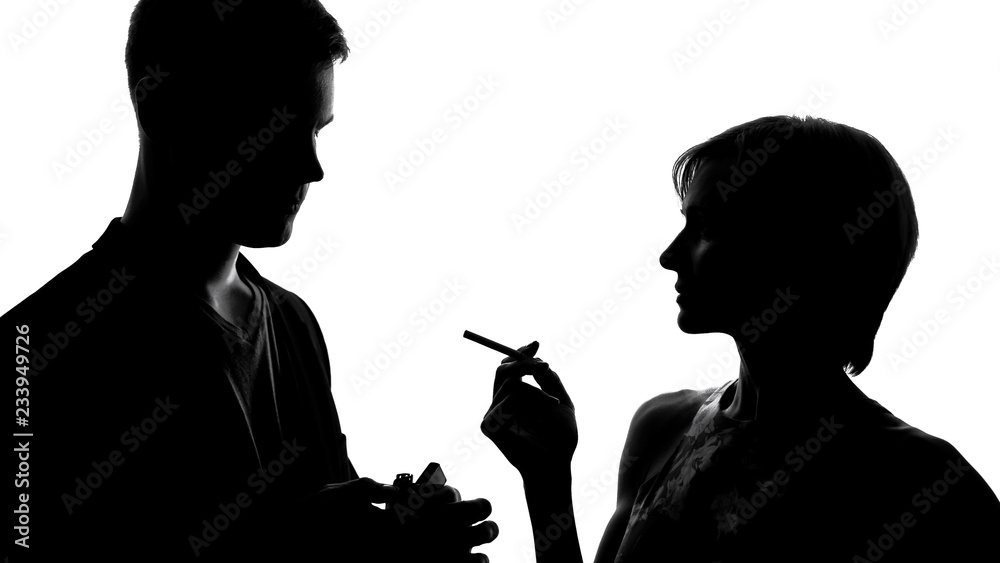 Young lady walking to man and lighting cigarette, flirting at party acquaintance