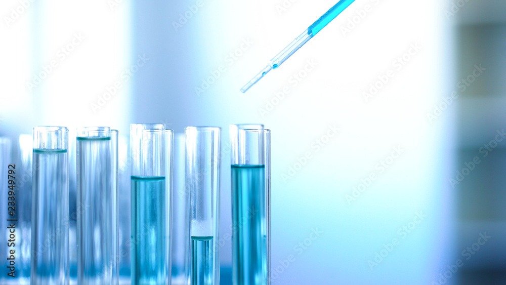 Laboratory worker pouring blue liquid in tubes, cleaning detergent production Laboratory worker pouring blue liquid in tubes, cleaning detergent production