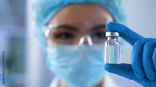 Photographie Lady scientist looking at ampoule with new medication, vaccination development