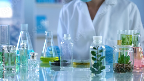 Scientist looking at liquid herbal extracts in bottle, organic perfumery testing
