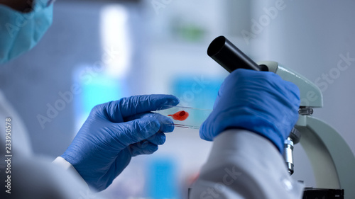 AIDS checkup, researcher preparing to examine blood sample under microscope