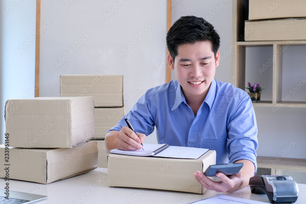 Young male business owner working at home checking box delivery to the customer.