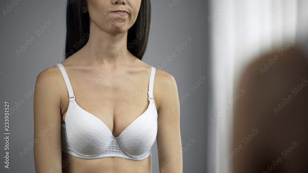 Fototapeta premium Female dissatisfied with her breast shape reflection in mirror, beauty, closeup