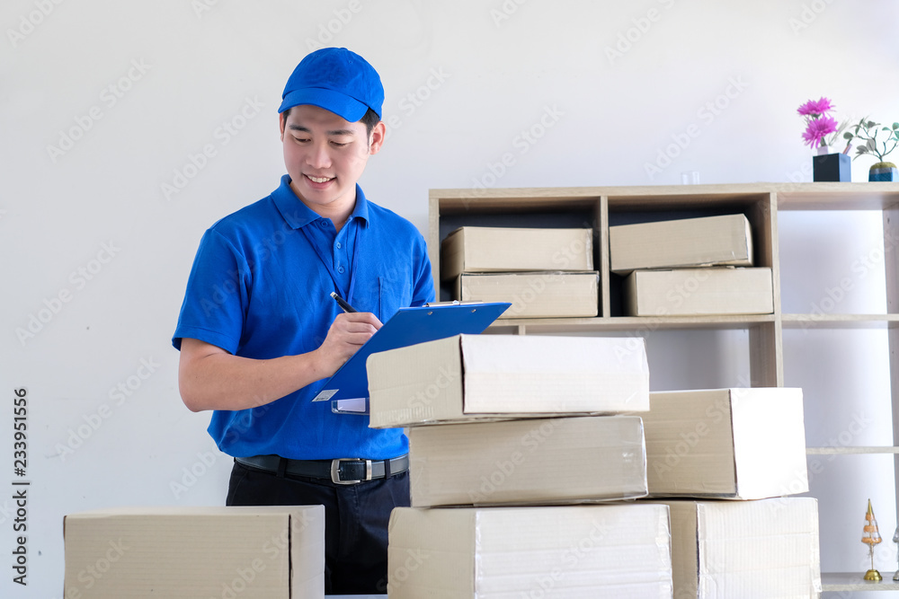 Young delivery man check the box before sending product. Young delivery man check the box before sending product.