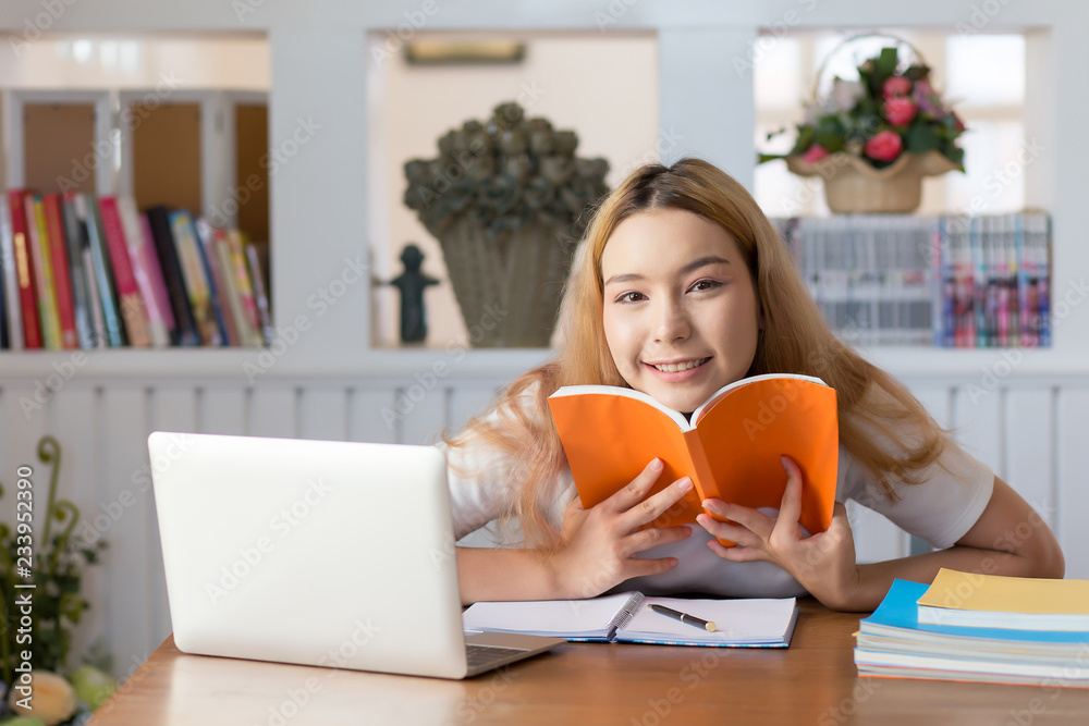 Female student sitting in library work. Smiling and laughing happily. Female student sitting in library work. Smiling and laughing happily.