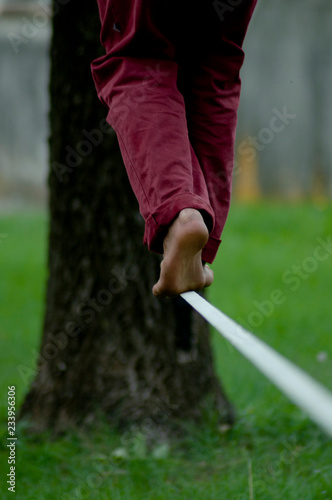 Man's feet close up while walking on slack line in a park. Complementary colors