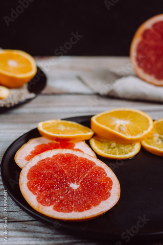 Delicious various types of citrus fruit in plates on wooden background