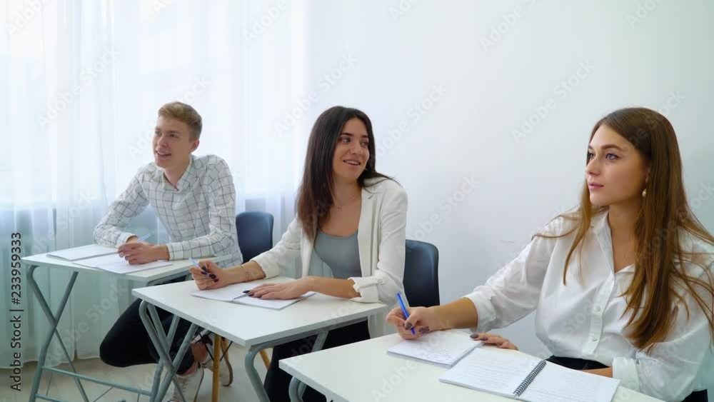 young people sitting at table working on school assignment in classroom. Students resolving tasks in teamwork. practice, learning, education, knowledge, development, growth concept young people sitting at table working on school assignment in classroom. Students resolving tasks in teamwork. practice, learning, education, knowledge, development, growth concept