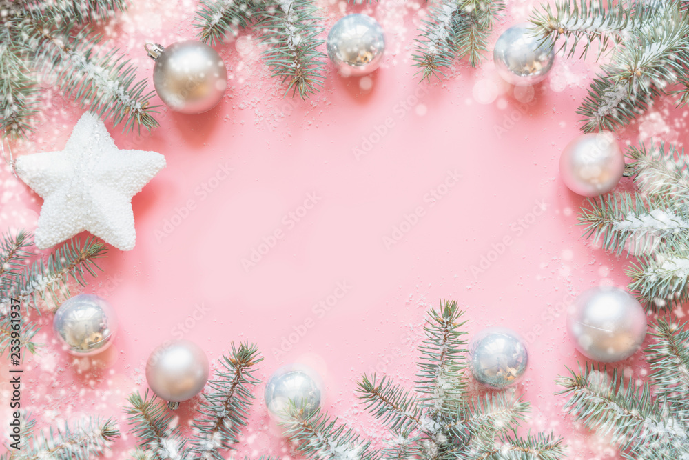 Fototapeta premium Christmas frame made of fir branches, festive white decorations,white star balls on pink table. Xmas background. Flat lay. Top view with copy space