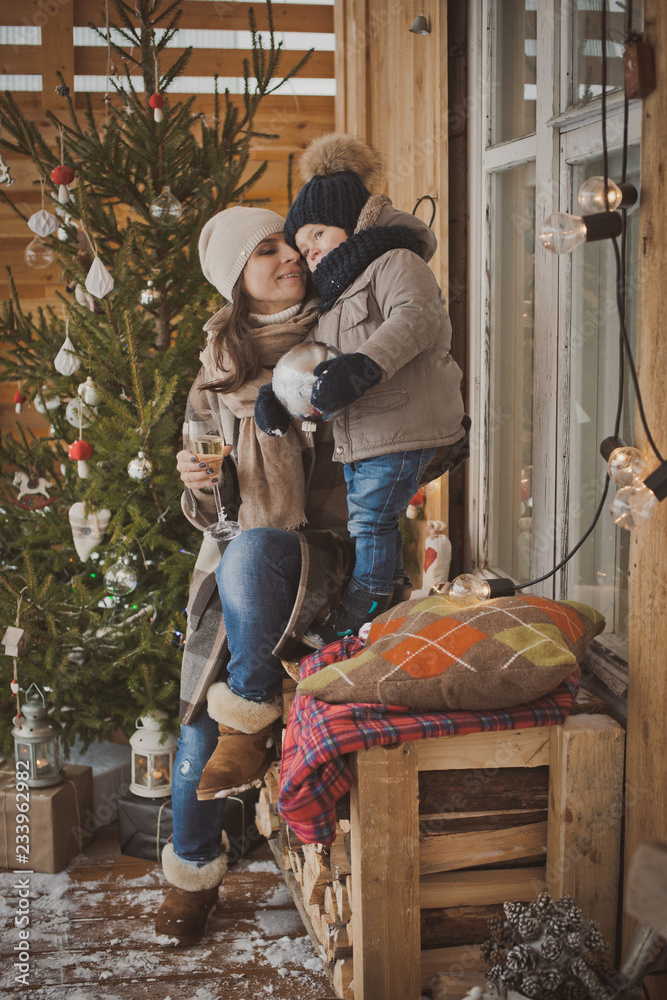 Russian young family enjoying their holiday time together, decorating Christmas tree outdoors in warm clothes, arranging the christmas lights and having fun. mother father and son meet new year