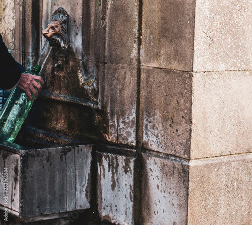 Woman collecting spring water from Buxton's St Anne's Well with plastic bottles.