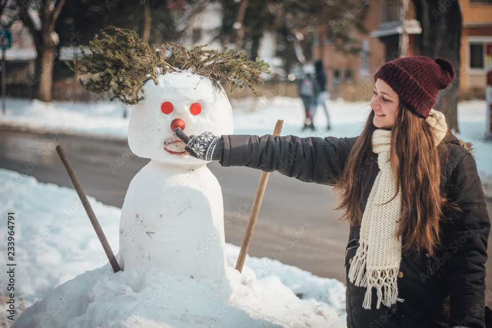 Happy girl touching nose of snowman