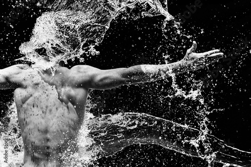 Portrait of a man's back with water flow splashing on him. Black and white.