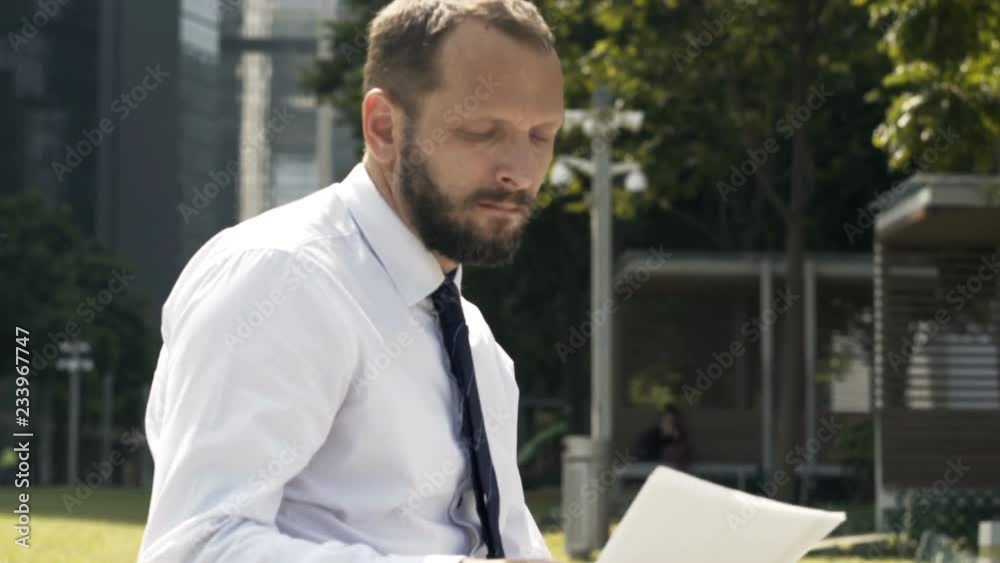 Young businessman working with documents sitting in city Young businessman working with documents sitting in city