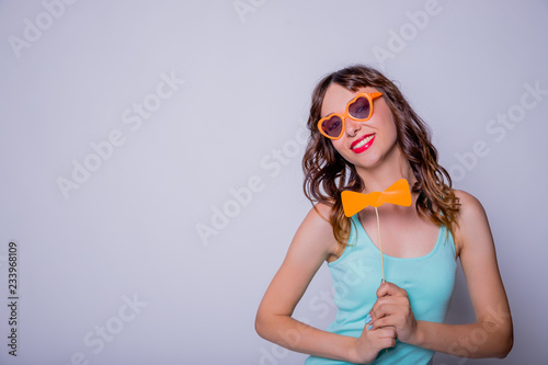 Portrait of crazy trendy chic with beaming smile having carton paper black cutout mustache on stick looking at camera isolated on white background.Paper accessories on a stick for a photo shoot on