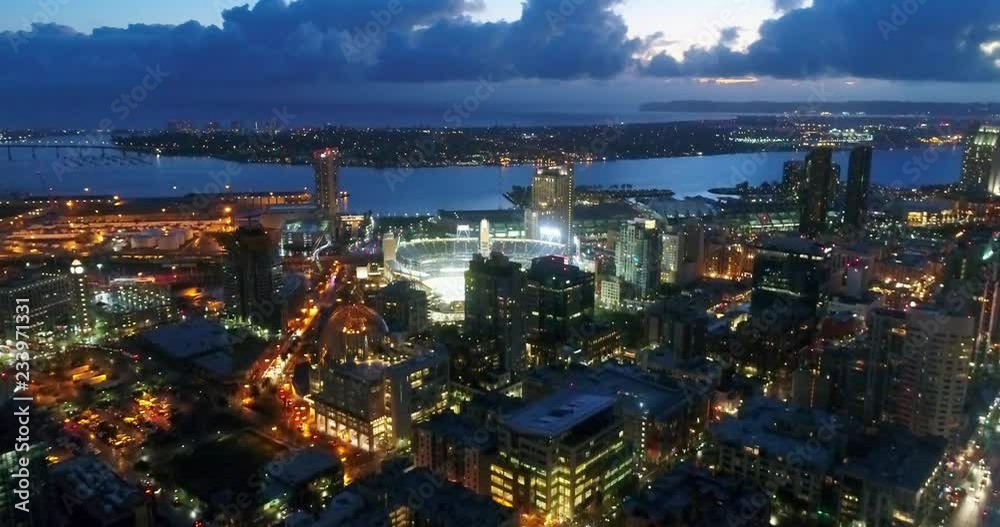 Aerial footage over downtown San Diego, California at night, looking towards Petco Park, with San Diego Bay and Coronado Island in the background.