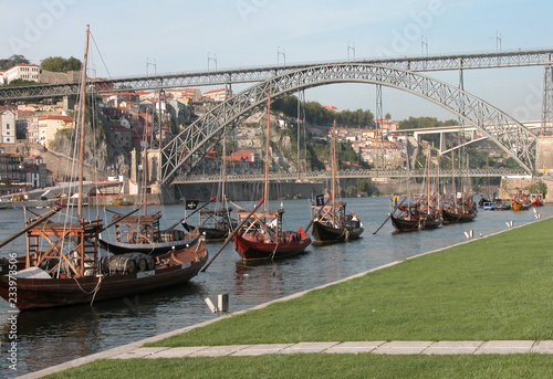 metal bridge in Porto, Portugal, above yhe Douro river and boats carrying wine barrels photo