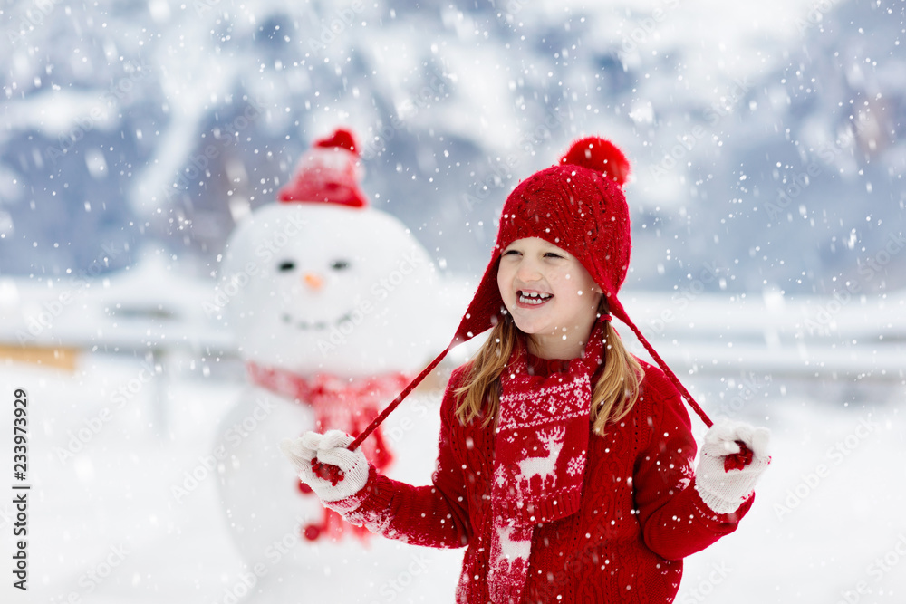 Child building snowman. Kids build snow man.