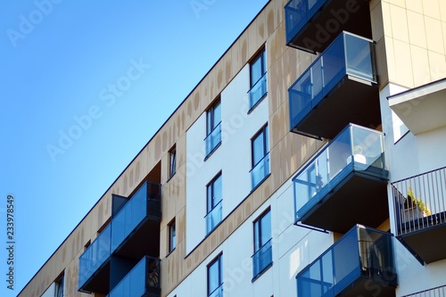 Fragment of a facade of a building with windows and balconies. Modern home with many flats.