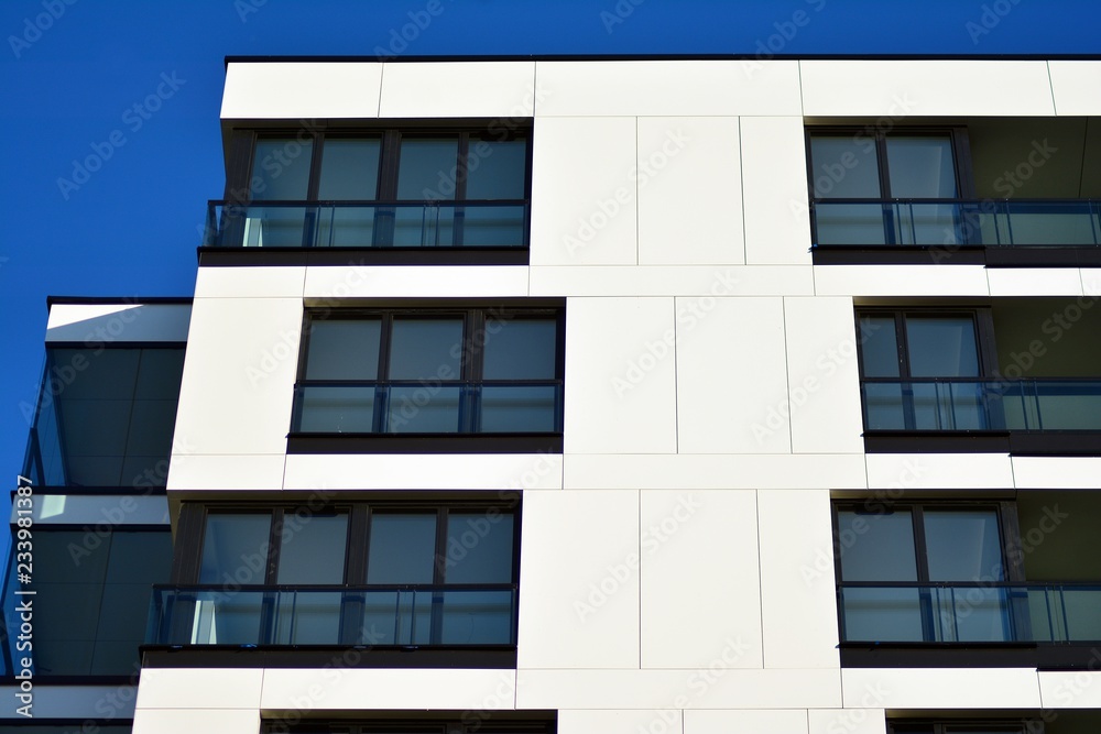 Fragment of a facade of a building with windows and balconies. Modern home with many flats.