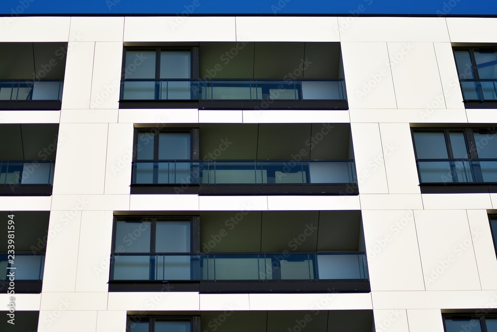 Fragment of a facade of a building with windows and balconies. Modern home with many flats.