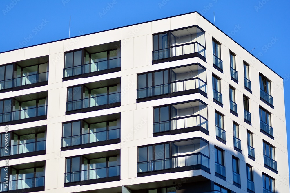 Fragment of a facade of a building with windows and balconies. Modern home with many flats.