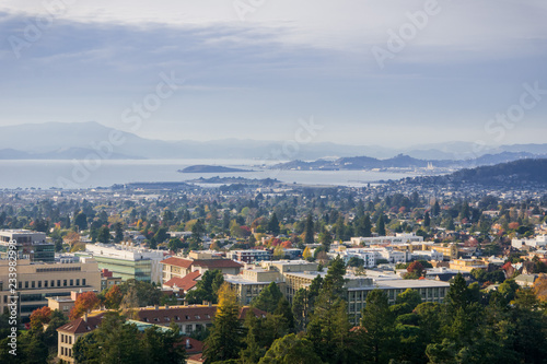 View towards Berkeley and Richmond on a sunny but hazy autumn day; University of California campus buildings in the foreground, San Francisco bay area, California