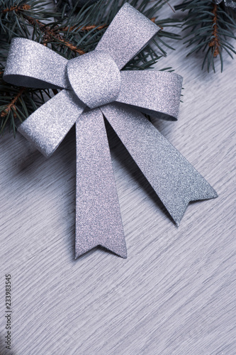 Silver bow on a background with a branch of the Christmas tree.