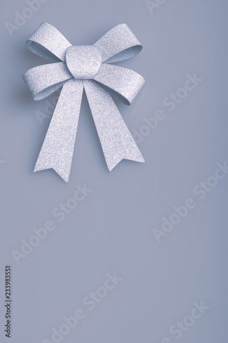 Silver bow on a light background in cold colors.