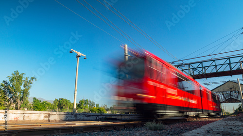 Red train traveling at a high speed on a sunny day without clouds