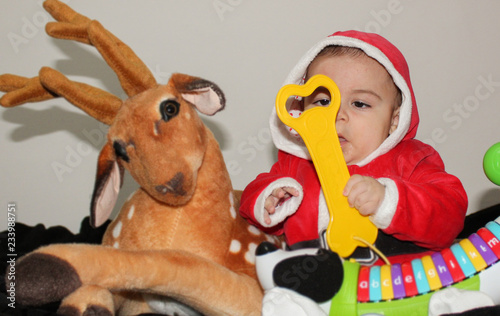 nine months old baby boy in santa clause suit with dear and toys © Starmarpro