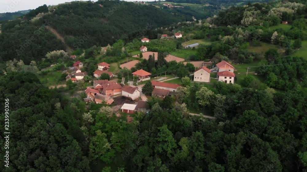 Aerial drone shot over the east european mountain village surrounded with forest in sunset. Lush green trees during Summer. Shot in 4K (UHD). Aerial drone shot over the east european mountain village surrounded with forest in sunset. Lush green trees during Summer. Shot in 4K (UHD).