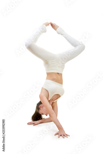 A young woman in a white suit performs acrobatic elements and yoga.