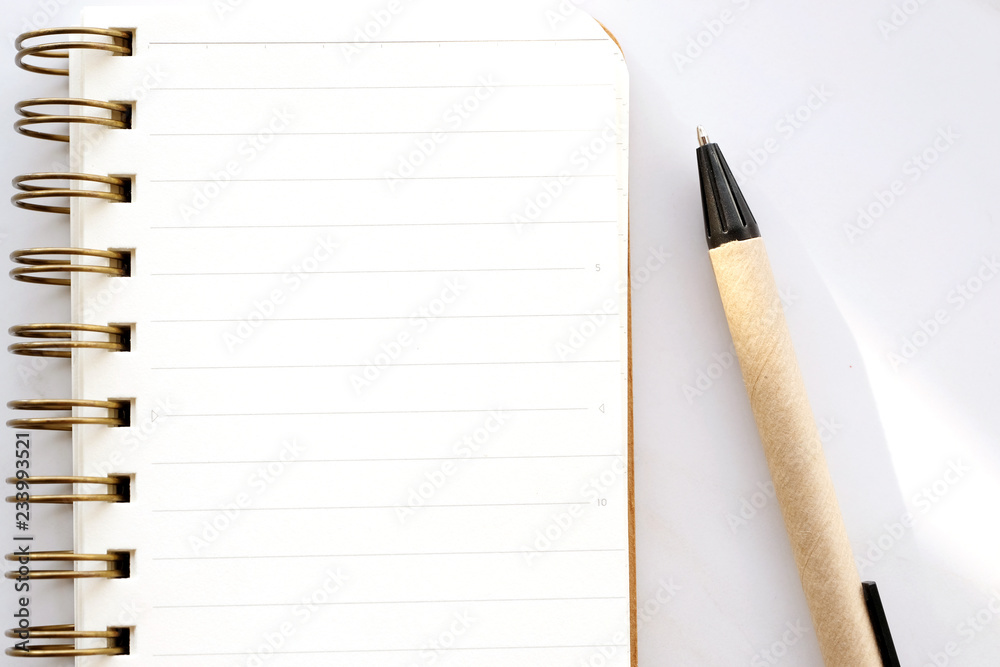 Blank notebook paper and pen on white marble background, with copy space for text, top view Blank notebook paper and pen on white marble background, with copy space for text, top view