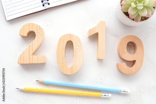 2019 wood letters, notebook paper and pencils on white marble table background, 2019 new year greeting card, banner, top view