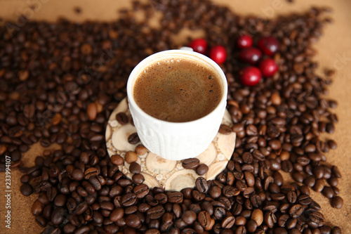 cup of coffee and coffee beans with red berries on wooden background