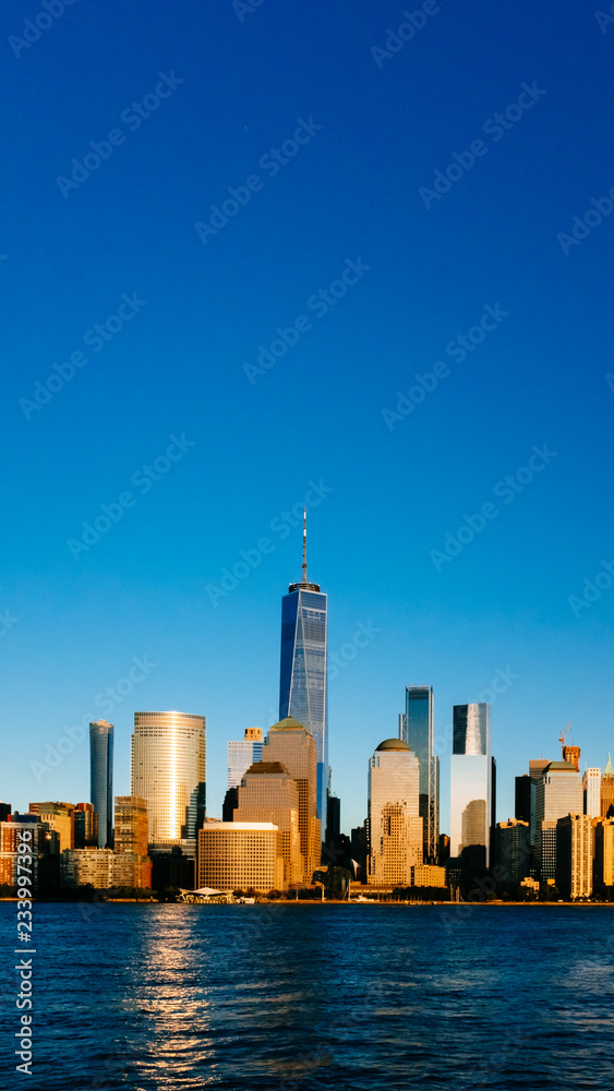 Skyline of downtown Manhattan over Hudson River under blue sky, at sunset, in New York City, USA