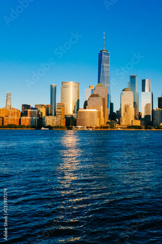 Skyline of downtown Manhattan over Hudson River under blue sky, at sunset, in New York City, USA © Mark Zhu
