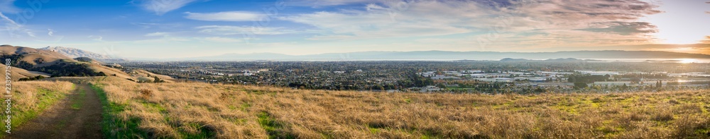 Panoramic view towards Fremont and Union City from Garin Dry Creek Pioneer Regional Park, San Francisco bay in the background, golden hills and hiking trail in the foreground, California