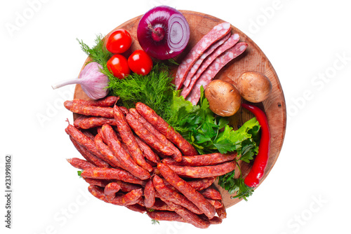 Hunting smoked sausages isolated on white background. Sausage with greens and vegetables on a wooden round board